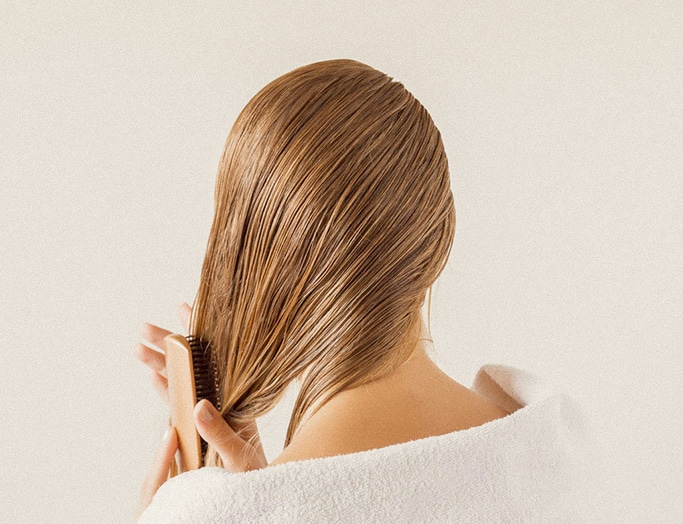 back of woman's head as she brushes thin hair